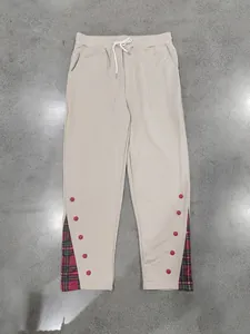 Vista frontale dei pantaloni beige da uomo con patchwork a quadri rossi e bottoni