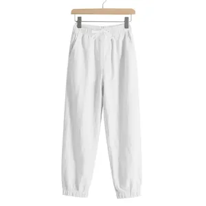 Detailed close-up of white linen jogger pants featuring drawstring waist and elastic cuffs