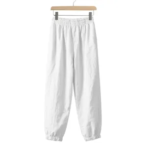 Close-up of white linen trousers with elastic waist and tapered cuffs on a wooden hanger
