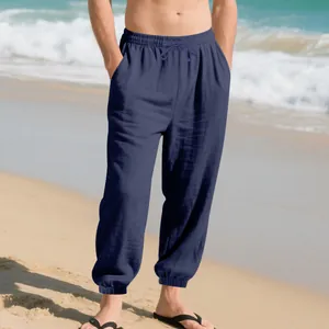 Model wearing navy blue loose linen jogger pants with drawstring on a sunny beach