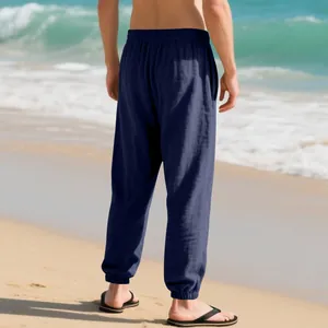 Back view of men's navy blue linen jogger pants on a sunny tropical beach background