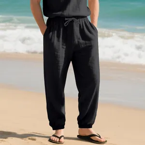 Detailed view of men's breathable black linen joggers with drawstring waist on a beach