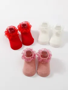 Close-up detail of breathable baby socks featuring elegant lace ruffles in red, white, and pink