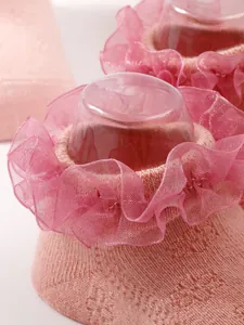 Close-up detail of pink baby socks with delicate ruffle lace trim for a princess style.