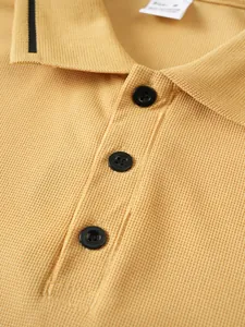 Close-up detail of yellow honeycomb textured polo shirt with black buttons and striped collar detail.
