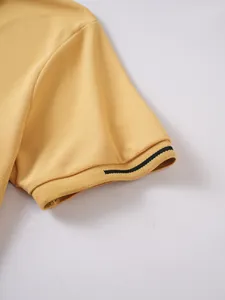 Close-up of yellow men's polo shirt ribbed sleeve cuff with black stripe detail