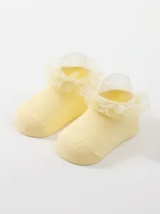 Close-up detail of yellow infant princess socks with elegant breathable lace ruffles