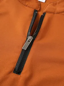 Gros plan détaillé montrant la fermeture éclair noire et la texture du tissu d'un t-shirt orange