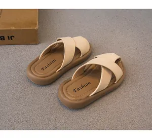 Primer plano de sandalias infantiles con correas cruzadas beige y suelas marrones
