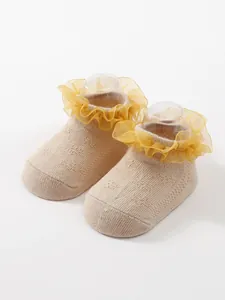 Detail view of breathable baby socks with yellow ruffled lace and knitted texture
