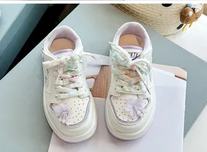 Detailansicht weißer Mädchen-Sneaker mit lila Blumenanhängern und bunten Schnürsenkeln