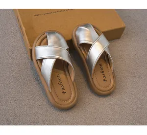 Primer plano de sandalias plateadas con tiras cruzadas para niñas y suelas marrones