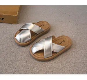 Detalle de sandalias plateadas para niños con correas cruzadas y suelas marrones suaves
