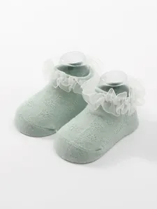 Close-up of soft breathable knit baby boat socks featuring elegant white lace ruffles