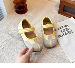 Detalle de bailarinas Tabi con punta dividida en amarillo y gris con correa de velcro ajustable