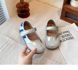 Zapatos Mary Jane plateados con punta dividida y tiras azules decorativas.
