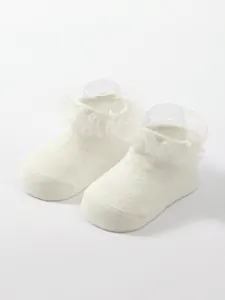 Detail of white breathable baby socks with elegant lace ruffles for a princess look