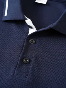 Close-up of a navy blue men's polo shirt collar featuring jacquard texture and buttons