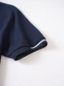 Macro view of navy polo shirt sleeve cuff featuring a white stripe and pique texture