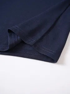 Macro detail of the navy blue piqué fabric and stitching on a men's polo shirt