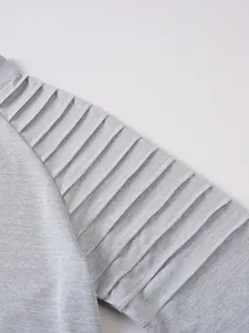 Détail rapproché d'un t-shirt gris à manches longues avec design plissé à l'épaule