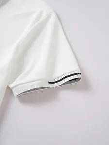Close-up view of a white polo shirt sleeve detail featuring a black striped ribbed cuff
