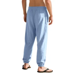 Back view of men's loose light blue linen jogger pants with elastic waist and cuffs.