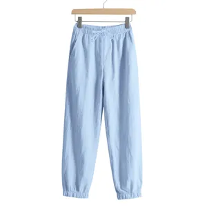 Detail of light blue linen joggers with elastic drawstring waist and cuffed hem.