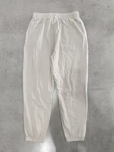 Detailed view of lightweight linen jogger pants in off-white on a textured background.