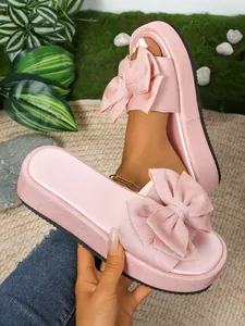 Primer plano de sandalias rosas de plataforma con lazo grande y detalle brillante