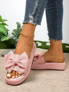 Vista detallada de sandalias de plataforma rosas con un lazo grande en los pies del modelo