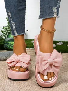 Primer plano de sandalias de plataforma rosa con lazos grandes en los pies