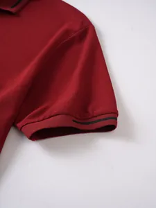 Close-up of the burgundy short sleeve cuff with black stripe detail on a men's polo shirt