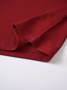 Close-up view of the stitched hem and jacquard texture of a burgundy men's Polo shirt