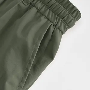 Detail shot of elastic waistband and side pocket on olive green men's trousers