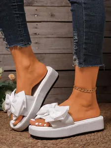 Primer plano de sandalias de plataforma blancas con lazo decorativo y textura fina