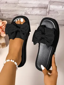 Primer plano de sandalias con plataforma negras con lazo grande y suela gruesa