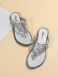 Detalle de chanclas plateadas con elegantes adornos florales y cómodas suelas blandas.