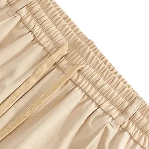 Detailed view of beige men's casual trousers featuring an elastic waistband and drawstring.