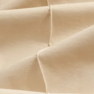 Macro view showing the high-quality beige twill fabric texture and fine stitching details of trousers