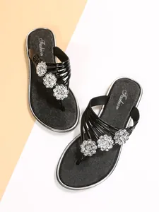 Primer plano de chanclas negras con flores plateadas y suela interior texturizada