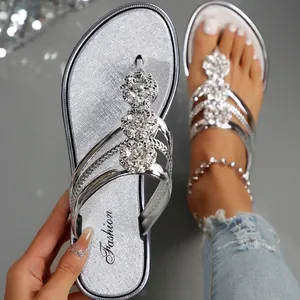 Primer plano de sandalias plateadas de dedo con flores brillantes de diamantes