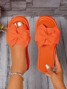 Primer plano de sandalia con plataforma de color naranja vibrante y detalle de lazo grande