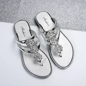 Primer plano de sandalias de dedo plateadas con flores brillantes de strass