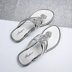 Vista detallada de chanclas plateadas con flores de pedrería brillantes para verano.