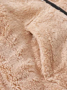 Detaillierte Makroansicht der weichen hellbraunen Sherpa-Fleece-Textur mit Reißverschluss
