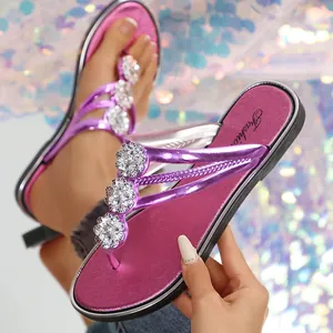 Vista detallata de modernas chanclas de color púrpura metálico con flores de strass brillantes