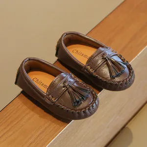 Nahaufnahme brauner Kinder-Loafer mit Lederstruktur und dekorativen Troddel-Details.