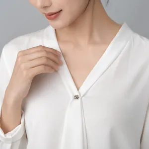 Elegante clip magnético para pañuelo y broche plateado en una blusa de seda blanca
