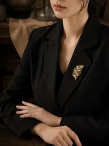 Vista detallada de un elegante broche en forma de hoja con pedrería sobre una chaqueta negra.